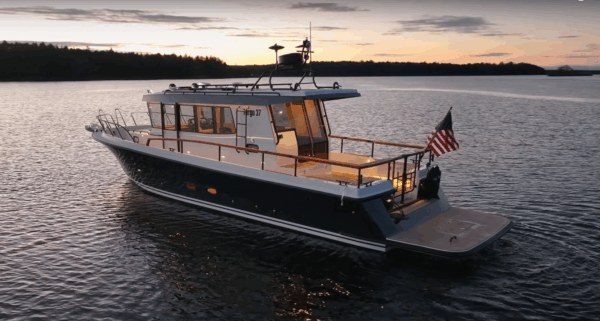 Targa 37 floating with an American flag on the stern just after sundown, with a golden sky and the Maine coast in the background.