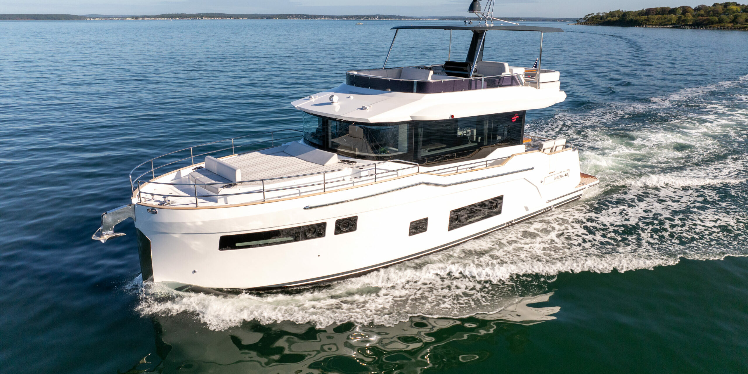 Sirena 48 Flybridge – Forward Port-Side Cruising View Forward port-side view of Sirena 48 flybridge cruising through green waters.