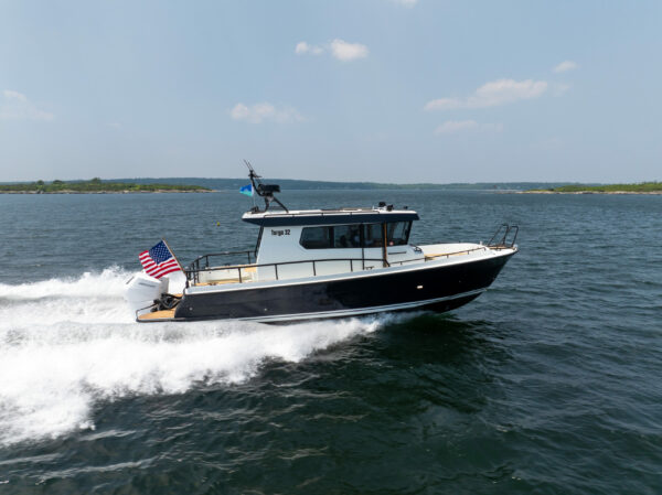 Targa 32 Outboard Side View in Casco Bay – East Coast Yacht Sales Side view of a Targa 32 Outboard cruising in Casco Bay, Maine, showing the full boat, twin Mercury 350 outboards, and an American flag flying from the stern.