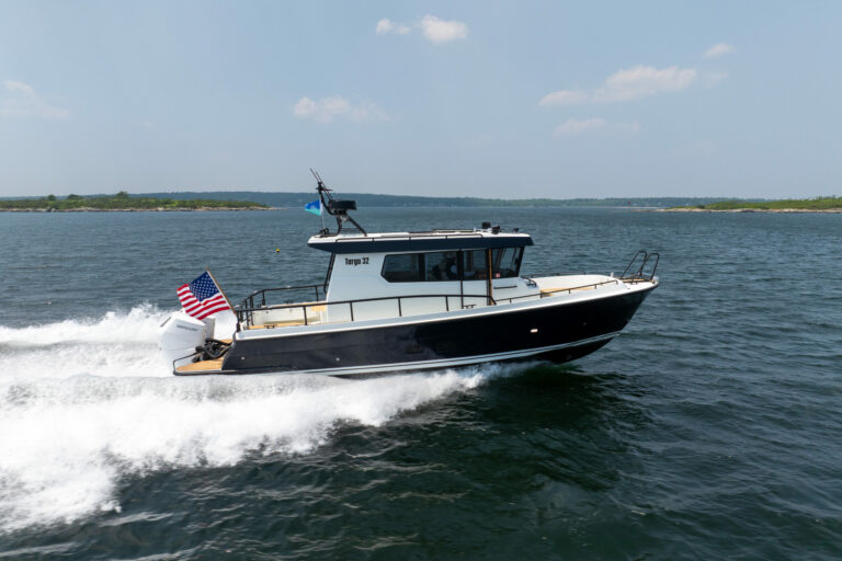 Targa 32 Outboard Side View in Casco Bay – East Coast Yacht Sales Side view of a Targa 32 Outboard cruising in Casco Bay, Maine, showing the full boat, twin Mercury 350 outboards, and an American flag flying from the stern.